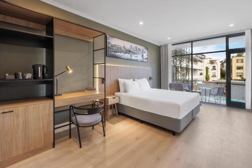 a hotel room with a bed and a desk and a balcony at Park Inn by Radisson Melbourne Carlton in Melbourne