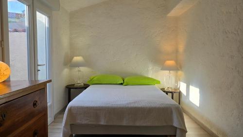a bedroom with a bed with two green pillows at Laure Cabasson in Bormes-les-Mimosas