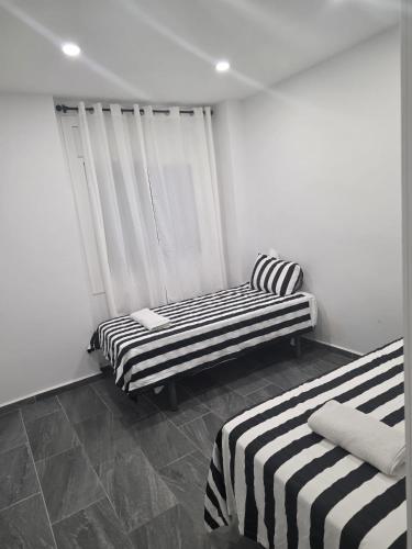 two beds in a room with black and white stripes at Apartamento Centro in Rubí