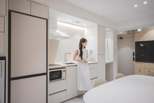 a woman standing in a kitchen with a cup of coffee at 더하다 in Busan