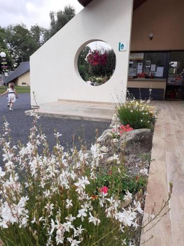 a little girl walking in front of a building with flowers at Tente lodge in Brassac