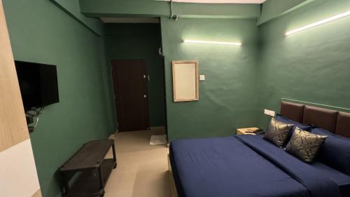 a bedroom with a blue bed and a green wall at FabHotel Metro Stay in Kolkata