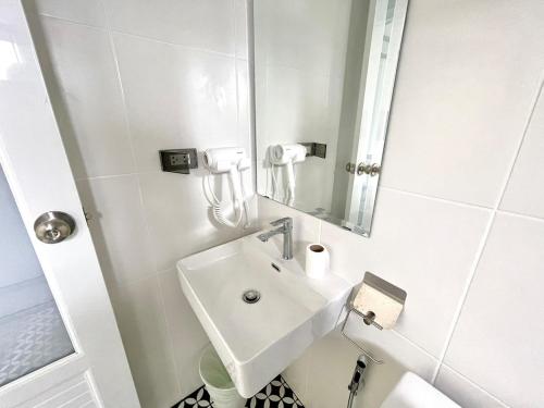 a white bathroom with a sink and a mirror at Milky house in Ban Bang Phai