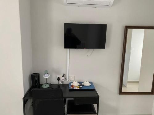 Ein Schreibtisch mit Fernseher an einer weißen Wand mit einem Schreibtisch sidx sidx sidx sidx in der Unterkunft The GL in Gaborone