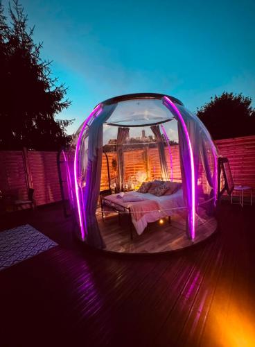 a bed in a bubble tent with purple lights at Reves2bulles in Ousse