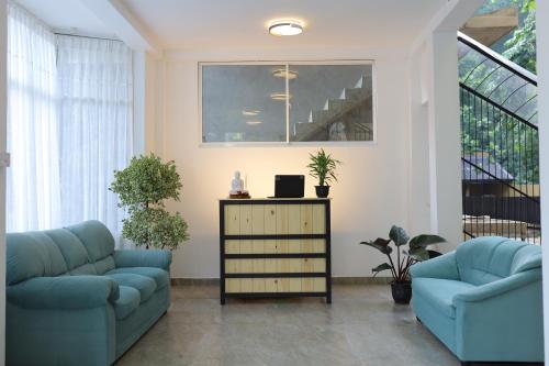 a living room with two blue couches and plants at Ayurya Wellness Retreat in Kandy