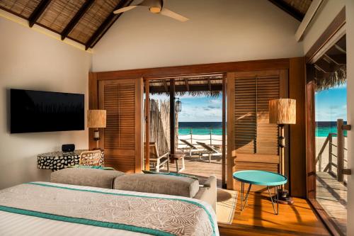 a bedroom with two beds and a view of the ocean at Constance Moofushi Maldives - All Inclusive in Himandhoo 