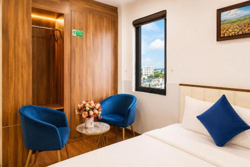 a hotel room with a bed and two blue chairs at Le Centre Pleiku Hotel in Pleiku