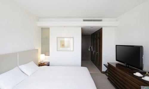 a bedroom with a bed and a flat screen tv at Geoje Samsung Hotel in Geoje