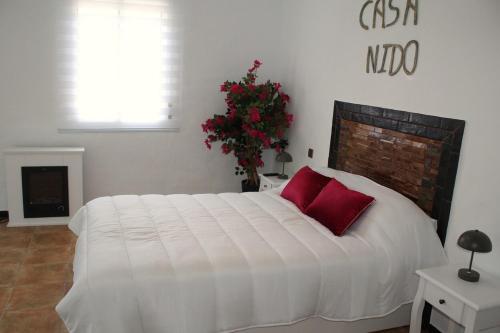 a bedroom with a large white bed with red pillows at Casa Nido in Ríogordo