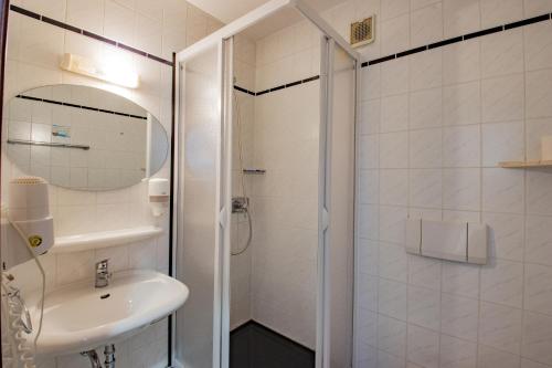 a white bathroom with a sink and a shower at Hotel garni Zwickau-Mosel in Mülsen