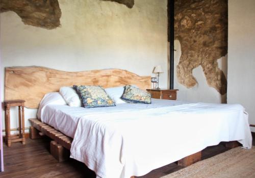 a bedroom with a white bed with a wooden headboard at Casa rural Más La Torreta con vistas al Pla de Vistabella cerca del Peñagolosa Pet Friendly niños gratis in Vistabella del Maestrazgo