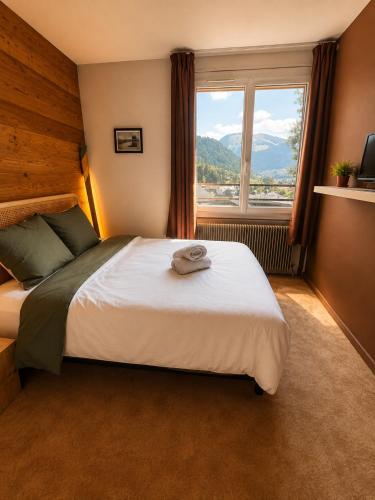 a bedroom with a large bed with a large window at 1861 Châtel Hostel in Châtel
