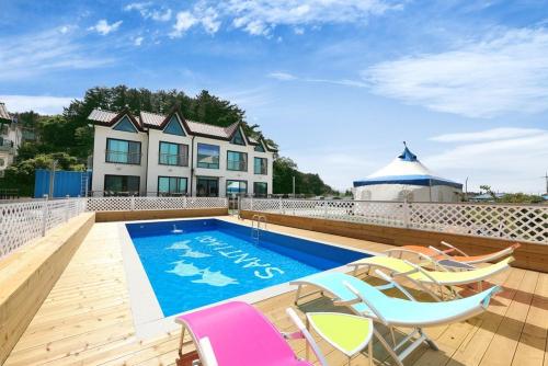 a swimming pool with chairs and a house at Samcheok santiago pension in Samcheok