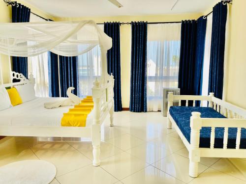 a bedroom with a white canopy bed and blue curtains at Elna's Nyali - Work & Unwind - Pool, Sea Views, AC & Fast Wi-Fi in Mombasa