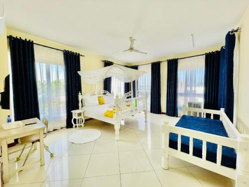 a white bedroom with two beds and a table at Elna's Nyali - Work & Unwind - Pool, Sea Views, AC & Fast Wi-Fi in Mombasa