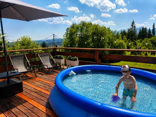a young boy standing in the water in a swimming pool at Willa Pachówka - tam, gdzie natura spotyka się z nowoczesnością in Bukowina Tatrzańska