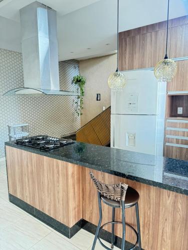 a kitchen with a counter with a stove and a stool at Área de Lazer in Limeira