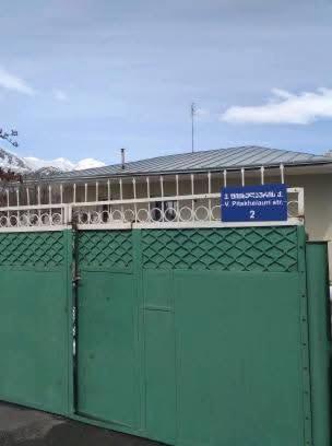 a building with green doors and a blue sign on it at Maias guest house in Kazbegi