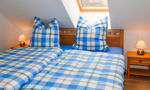two beds in a bedroom with blue and white sheets at Am Kranichland in Wieck