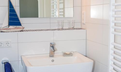 a bathroom with a sink and a sailboat on a shelf at Am Kranichland in Wieck