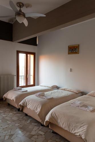 a room with three beds and a ceiling fan at Debre Mariam Guest House in Bologna
