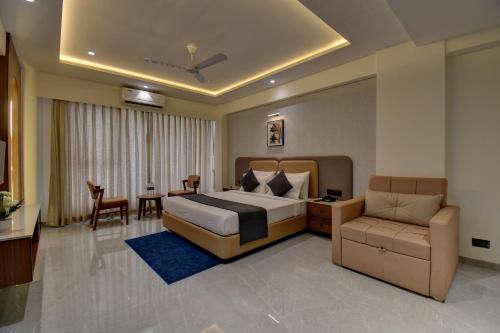 a bedroom with a bed and a couch and a table at Hotel Sai Mahima, Near Sai Baba Temple in Shirdi