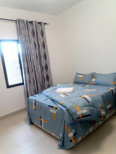 a bedroom with a bed with blue comforter and a window at Flora House in Maputo