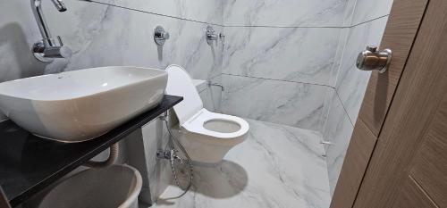 a white bathroom with a sink and a toilet at Hotel Centrum in Surendranagar