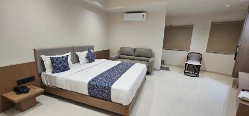 a bedroom with a large bed and a chair at Hotel Centrum in Surendranagar