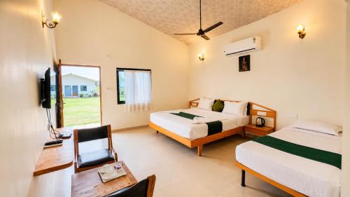 a bedroom with two beds and a desk and a tv at Unity Sunrise Resort Statue of Unity Ekta Nagar in Kevadia