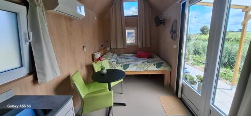 a small room with a bed and a table and a window at Buorkerijhûske A - Tussen Wad en Weide in Hallum