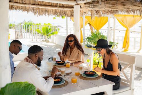 a group of people sitting around a table eating food at ZAN Uhuru Beach in Jambiani