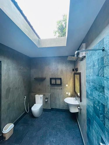 a bathroom with a toilet and a sink and a skylight at Ela Addara Green Villa in Sigiriya