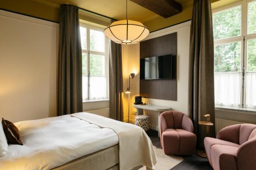 a hotel room with a bed and two chairs at Hotel Kasteel Doenrade in Doenrade