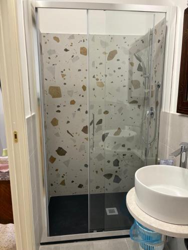 a shower with a glass door next to a sink at Atelier Peretti in Alghero