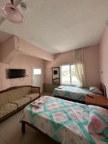 a bedroom with two beds and a couch and a tv at Yalçın Pansiyon in Silifke
