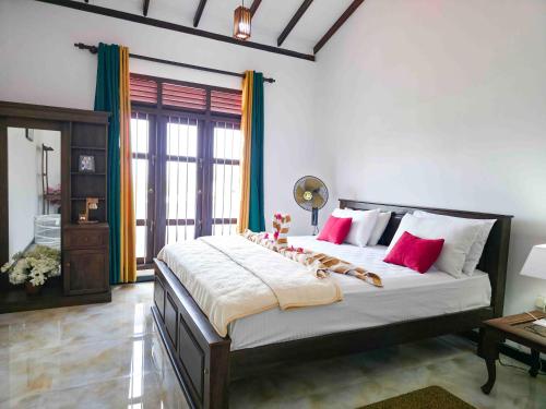 a bedroom with a large bed with red and white pillows at Dishan Green Retreat in Ambalangoda