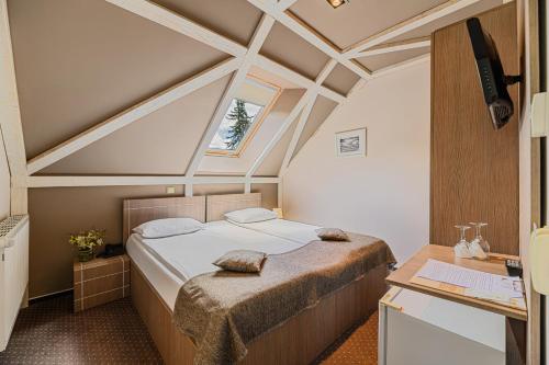 a bedroom with a bed and a desk and a window at Complex Hotelier COTA O MIE in Sinaia