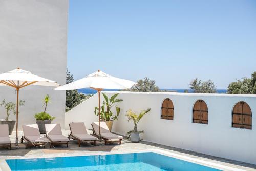 a pool with chairs and umbrellas next to a building at Casa Evita in Gennadi