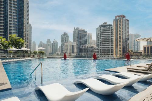 a swimming pool with white chairs and a city skyline at InterContinental Dubai Marina by IHG in Dubai