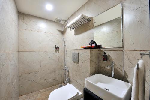 a bathroom with a sink and a toilet and a mirror at Ginger Somnath in Somnath