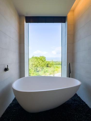 a large white bath tub in a bathroom with a window at Villa Mori - Odin Hills in Kutchan