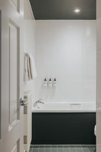 a white bathroom with a tub and a sink at Arthouse Glasgow - Newly Refurbished in Glasgow