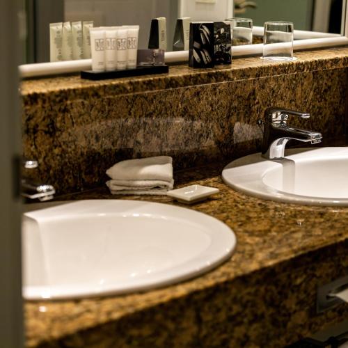 a bathroom counter with a white sink and a mirror at MAXIMILIAN Grand Hotel in Bad Griesbach
