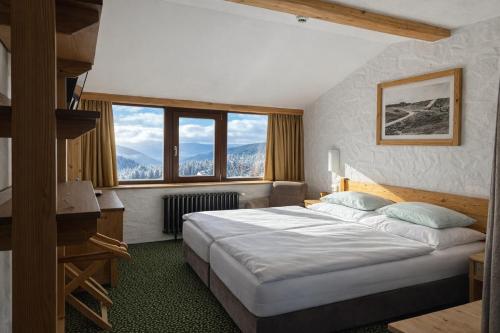 a bedroom with a large bed with a large window at Erlebachova Bouda, hotel - Resort Svatý František in Špindlerův Mlýn