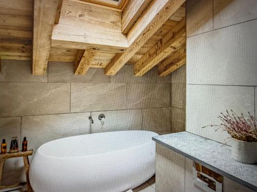 a white bath tub in a bathroom with wooden ceilings at Crystal Lodge St Moritz in St. Moritz