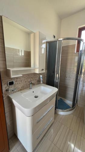 a bathroom with a white sink and a shower at Vacation Home Hoxha in Rrotull