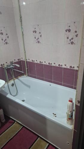 a bath tub in a bathroom with purple tiles at Махамбета in Atyrau