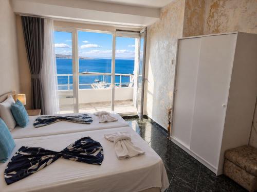 two beds in a hotel room with a view of the ocean at ORION Guest House in Sozopol
